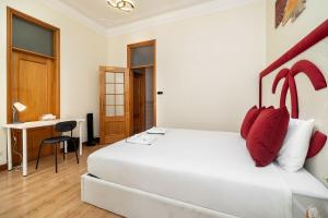 a bedroom with a large white bed with red pillows at Anjos Station Lisbon Hostel in Lisbon