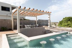 una pérgola sobre una piscina en una casa en Yaxche by Andiani Travel, en Isla Mujeres