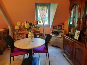 eine Küche mit einem Tisch und Stühlen mit einer Vase aus Blumen in der Unterkunft Chambre d hôte les bosquets in Caugé