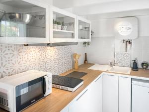 a kitchen with white cabinets and a microwave at Duplex au vert près de Royan - Appartement 4 in Médis