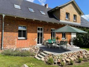 a brick house with a table and an umbrella at Ferienwohnung am Rathsburgsee in Gramzow
