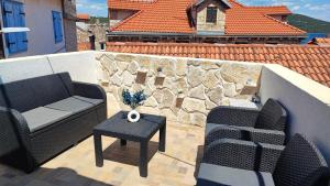 a patio with two chairs and a table and a stone wall at Tisno Stone House on the Cove in Tisno