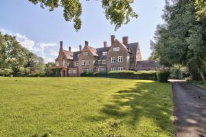 an old house with a grassy field in front of it at Alward House by Group Retreats in Salisbury