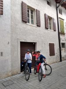 three people on bikes in front of a building at Affittacamere Casa Bliss in Venzone