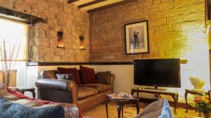 a living room with a couch and a television at Commerce Cottage Rooms in Ripley