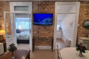 sala de estar con TV en una pared de ladrillo en Beachfront Sunset View Apartment - The Coachhouse, en Narrabeen