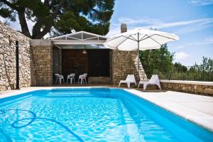 a swimming pool with an umbrella and chairs at La Torreta de Aitana in Confrides