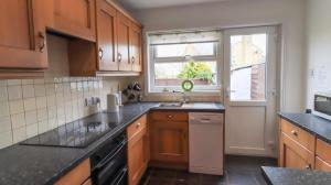 a kitchen with wooden cabinets and a sink and a window at Commerce Cottage Rooms in Ripley +12 photos