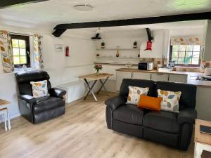 ein Wohnzimmer mit Couch und Küche in der Unterkunft Windbury Cottage in Bideford