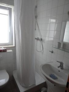 baño blanco con ducha y lavamanos en Ferienwohnung Toska, en Pfaffenweiler