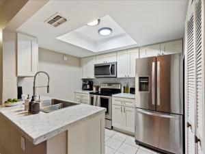 a kitchen with a stainless steel refrigerator and white cabinets at Artist's Tower Townhome Just Renovated w Loft in Gainesville