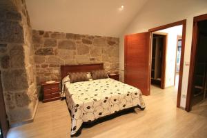 a bedroom with a bed and a stone wall at Casa en Fontecova in Cuntis