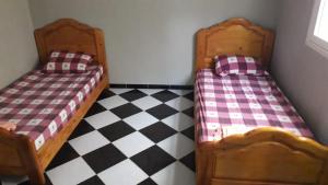 two beds in a room with a checkered floor at Appartement de vacances 2 chambres à Saidia 2 min de la plage à pied in Saidia 
