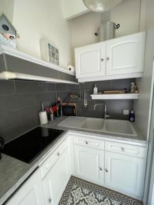 a kitchen with white cabinets and a sink at Maison de Vacances des Centaurées in La Guérinière +5 photos