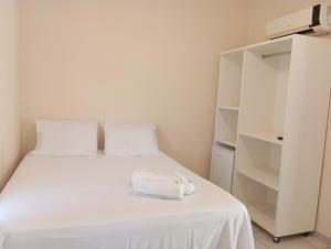 a white bed with a towel on top of it at Pousada Piri carvalho in Pirenópolis