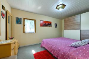 a bedroom with a purple bed and a window at Kuća Viola, traditional wooden house in Tuhelj in Tuhelj