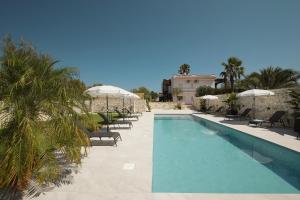 a swimming pool with chairs and umbrellas at Villa Merilusi Apartments in Fontane Bianche