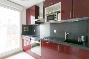 a kitchen with red cabinets and a sink and a microwave at Cozy & Quiet Getaway Just 300m from Paris with Free Private Parking in Gentilly