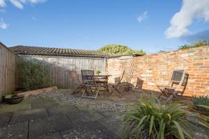 d'une terrasse avec des chaises, une table et un mur en briques. dans l'établissement Sloe Gin Cottage, à Heacham
