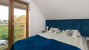 a bedroom with a bed with a blue headboard and a window at Dom Gościnny 2 Ogrodowa in Wiślinka