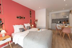 a bedroom with a red wall with a bed and a table at Les Lodges des Forges - Appartements Climatisés in Strasbourg