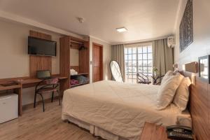 a hotel room with a large bed and a desk at Hotel Mont Blanc in Bento Gonçalves