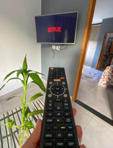 a person holding a remote control in front of a television at Pousada Pinhão Roxo in Porto Seguro