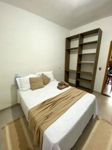 a bedroom with a large white bed and shelves at Pousada Pinhão Roxo in Porto Seguro +5 photos