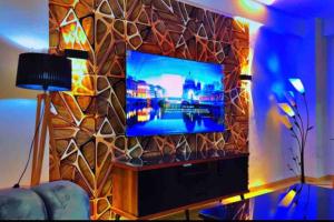 贝贾亚Appartement standing的客厅设有石墙,配有平面电视。