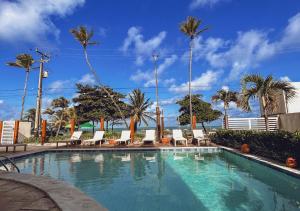 una piscina con sillas y palmeras en Kastel Jampa Hotel, en João Pessoa