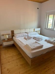 a bedroom with a bed with white sheets and a window at Central Apartment Gjirokaster in Gjirokastër