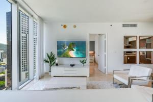 a living room with a tv on a white wall at ICON Brickell Miami- 2 bedroom Condo with City and water views! in Miami