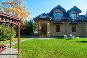a brick house with two chairs in the yard at Willa Bursztynowa 1 in Poddąbie
