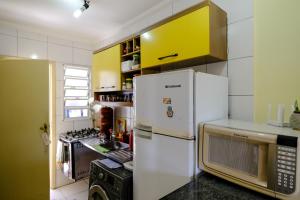 a kitchen with a white refrigerator and a stove at Apt 5 min da praia andando in Bertioga