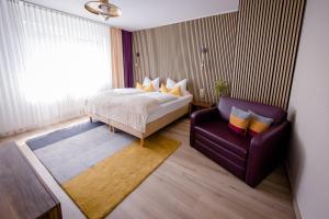 a bedroom with a bed and a purple chair at Franconia City Hotel in Nuremberg