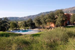 a swimming pool in a field with mountains in the background at Finca el Rabilargo in Arroyomolinos de Montánchez