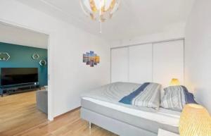 a white bedroom with a bed and a television at Sentral leilighet til utleie in Stavanger