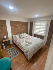 a bedroom with a large bed and a brick wall at Casa equipada y acogedora in Vallenar