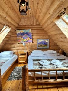 a bedroom with two beds in a log cabin at Будинок Художника in Synevyrsʼka Polyana