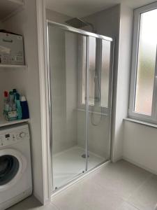 a glass shower in a bathroom with a washing machine at Maison cosy in Mauzé-sur-le-Mignon +12 photos