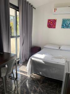 a bedroom with a bed and a desk and a window at Hotel Pousada Do Sol II in Aragarças
