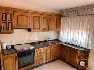 a kitchen with wooden cabinets and a sink at Ático Calvo Sotelo 217 in Sarria +16 photos