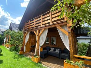 Casa con terraza de madera y sofá en Babie Domki, en Zawoja