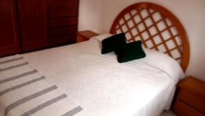 un letto bianco con due cuscini neri sopra di Casita Playa Mansa a Punta del Este