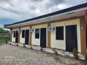 a small house with black shuttered windows and potted plants at Bryanne's Place in Tacloban