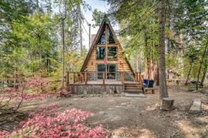 eine Blockhütte im Wald mit einer Veranda und einer Terrasse in der Unterkunft Dogwood Peak Mid-century A-frame With Ac Style in Shaver Lake