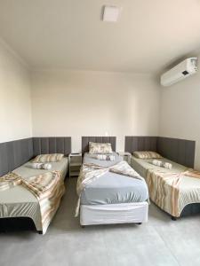 a room with three beds in it at Pousada Pôr Do Sol Varginha in Varginha
