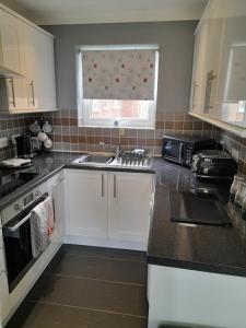 a kitchen with white cabinets and a sink and a window at clifftop villa 47 in Corton +5 photos