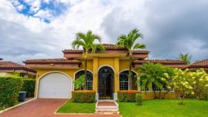 a yellow house with palm trees and a garage at Villa Felicidad By Vacation Pura Vida in Esterillos