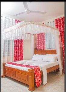 a bedroom with a canopy bed with red curtains at Little Haven Nyali mombasa in Mombasa